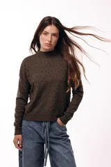 Sweater de tejido de punto con textura de pequeños relieves circulares, cuello redondo y mangas largas. Presenta un calce relajado con puños y ruedo acanalados.