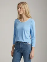 Remera de modal color celeste, con cuello redondo y mangas 3/4. Presenta un aplique bordado blanco en el cuello, ruedo y puños.