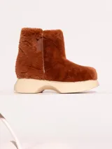 Bota de media caña color marrón, realizada en pelo sintético con detalles en cuero vacuno y suela de eva. El interior está forrado en cuero vacuno.
