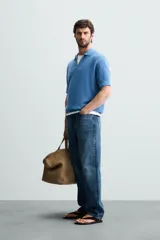 Polo de manga corta, color azul medio, tejido en punto perlado con cuello solapa y cierre frontal de cremallera.