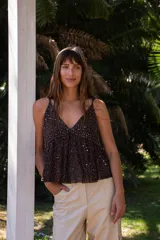 Blusa de tirantes finos con escote en V, confeccionada en gasa fluida color marrón. Presenta un diseño con bordado de lentejuelas y canutillos en el busto y líneas verticales de pedrería a lo largo del cuerpo.