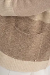 Cardigan abierto de punto con diseño de bloques de color en tonos beige, marrón y bordó. Presenta mangas largas, corte recto y bolsillos frontales aplicados.