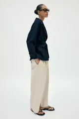 Chaqueta estilo trench corta color azul marino confeccionada con lino. Cuenta con cuello solapa, manga larga con trabilla, bolsillos delanteros de vivo y cierre frontal con lazada ajustable en la cintura.