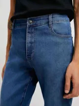 Pantalón de jean corte skinny, color azul medio, con diseño de cinco bolsillos y cierre frontal con botón y cremallera.