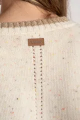 Sweater de lana color crema con efecto tweed, de calce oversize y cuello redondo. Presenta bloques de color en la parte inferior, puños y laterales de las mangas en tono beige con textura acanalada y detalles brillantes.
