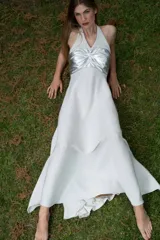 Vestido largo con pechera de cuero metalizado y falda tejida con hilo de lurex brillante. Presenta un diseño de cuello halter y corte fluido.