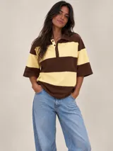 Remera polo de manga corta con diseño de franjas horizontales anchas en marrón y amarillo claro, cuello camisero y cartera con botones.