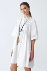 Camisa blanca de poplín de algodón, corte amplio, cuello mao y botones. Tiene recortes con detalles fruncidos en el delantero, espalda y puños.