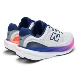 Championes de running New Balance modelo 1080v15, con capellada de malla transpirable en color blanco. Presenta una mediasuela con tecnología de amortiguación degradada en tonos azul y fucsia, y detalles en azul marino en el logo lateral, cordones y talón.