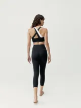 Top deportivo bicolor negro y blanco con asimetría, sujeción media-alta y tirantes cruzados. Confeccionado en tejido Shape_Tech con interior de mesh y copas extraíbles.