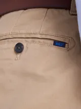 Pantalón de gabardina color azul marino, de corte recto y estilo clásico, con cierre de botón y cremallera, y trabillas para cinturón.