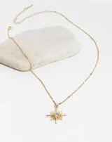 Collar dorado con dije en forma de sol con strass en el centro.