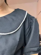 Blusa negra de lino con cuello Peter Pan blanco y mangas cortas abullonadas.