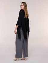 Poncho de calce holgado color marrón, confeccionado en tejido fino de punto suave, con cuello redondo y diseño de caídas laterales amplias de ruedo asimétrico.