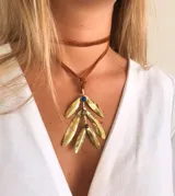 Collar con gargantilla de cuero marrón y colgante dorado con forma de hojas y piedras de colores.