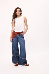 Musculosa blanca de algodón y lino, con tablas verticales en el frente y lazos laterales para regular el ajuste.