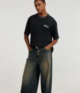 Pantalón mega baggy de corte holgado, confeccionado en jean gris con efecto deslavado. Presenta cintura con trabillas y diseño de tiro medio.