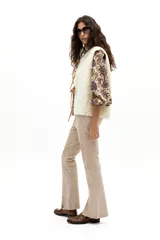 Pantalón de gamuza color arena, de corte recto con tajos en el ruedo. Tiene cintura de tiro medio con elástico interno y cierre frontal con gancho metálico escondido.