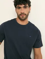 Remera básica de algodón color beige, de manga corta, con cuello redondo y un pequeño detalle bordado en el pecho.