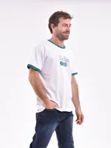 Remera blanca de mangas cortas con cuello y puños en color verde. Estampado frontal con texto y pelotas de tenis.