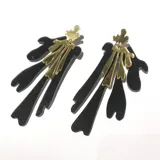 Aros colgantes con base dorada y piezas colgantes de acrílico negro con glitter.