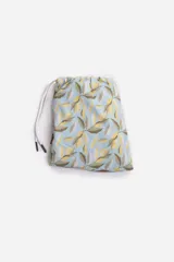 Short de baño celeste con estampado de hojas pequeñas en tonos verdes y blancos. Cuenta con cintura elástica con cordón ajustable, bolsillos laterales y un parche circular con logo en la parte inferior.