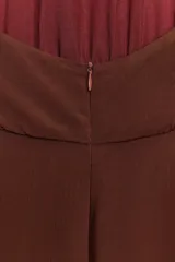 Vestido midi color marrón, con cuello halter que se anuda en la nuca, escote drapeado y frunces en el delantero. La falda es recta y presenta una abertura lateral.