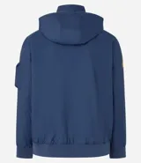 Campera rompevientos azul marino con capucha, cierre frontal y bolsillos laterales. Presenta estampado de NASA en el pecho, parche de bandera estadounidense en la manga y bolsillo utilitario en el brazo.