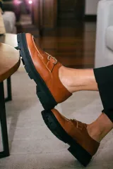 Mocasines de cuero color verde oliva con suela track negra de plataforma. Presentan una tira decorativa sobre el empeine con hebilla metálica dorada ajustable en el lateral.