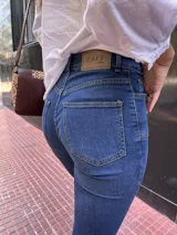 Pantalón de jean azul oscuro, corte recto, tiro alto y detalles de costuras en la parte superior.