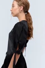 Top negro con escote en V, mangas abullonadas con lazos y cuerpo con lurex plateado.