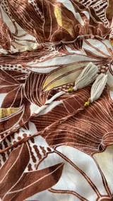 Vestido largo estampado con cuello halter y escote pronunciado en V. Presenta un estampado botánico en tonos marrones y beige, con falda amplia con volados en el ruedo.