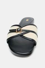 Sandalia plana color crudo con detalle de tira con hebilla dorada en la parte delantera.