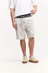 Short de baño estilo surf color gris, de largo medio, con estampado geométrico abstracto y cordón ajustable en la cintura. Incluye bolsillo trasero con solapa.