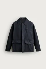 Sobrecamisa regular fit confeccionada en tejido de algodón negro con estructura canvas. Tiene cuello solapa, manga larga con puño abotonado, bolsillos de plastrón con solapa en la cadera y un bolsillo en el pecho. Cierre frontal con botones ocultos bajo solapa.