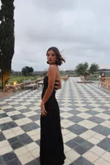 Vestido largo strapless de encaje negro con transparencias y espalda descubierta con tiras cruzadas, de corte entallado y falda de caída suelta.