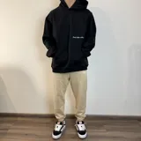Pantalón tipo jogger de algodón color beige, con puños elásticos en los tobillos y estampa pequeña en el frente con el texto 'BUENA VIBRA EST. 2018'.