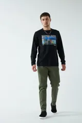 Pantalón de gabardina color verde militar, corte recto, con bolsillos laterales y traseros. Se ajusta a la cintura con cinturón de cuero marrón.