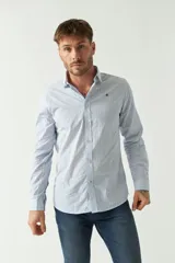 Camisa de hombre de corte slim fit, confeccionada en algodón con diseño de rayas verticales finas en tonos claros. Presenta cuello clásico, cierre frontal con botones y logo bordado en el pecho.