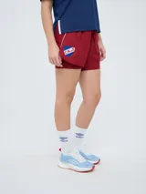 Short deportivo azul marino de mujer con calza interior celeste. Cuenta con cintura elástica ajustable con cordón y detalles de la marca Umbro y del Club Nacional de Football.