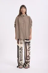 Camisa de manga larga color marrón claro, con cuello clásico, botones frontales y diseño holgado.