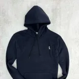 Canguro negro con capucha y bolsillo delantero tipo canguro. Tiene un pequeño logo bordado en el pecho.