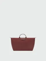 Bolso de viaje de gran tamaño, modelo Le Pliage One de Longchamp, en color marrón. Presenta el diseño icónico de la marca con solapa de cuero, asas cortas y cierre de cremallera superior.