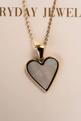 Collar con cadena dorada y dije en forma de corazón con interior de nácar.