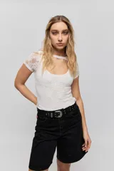 Top de encaje blanco con diseño ajustado al cuerpo, mangas cortas y detalle de cut-out en el escote.