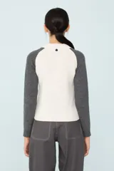 Sweater de punto bicolor, con cuerpo blanco con diseño de trenzas y mangas ranglan grises.