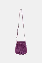 Mini bandolera de piel color morado, de diseño tipo saco con cierre fruncido y cordón ajustable con borlas en el extremo. Cuenta con asa larga ajustable y detalles metálicos dorados.