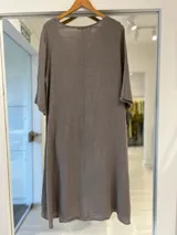 Vestido midi color visón con cuello en V, mangas tres cuartos y corte amplio y fluido con bolsillos laterales.