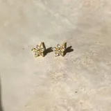 Par de aros dorados con forma de flor de cinco pétalos, con incrustaciones de circonitas blancas.