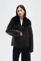 Chaqueta de eco-cuero negro con interior y cuello de piel sintética, diseño holgado, manga larga y cierre frontal con un botón.